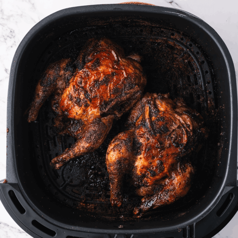 Cooked frozen Cornish hens in the air fryer basket.