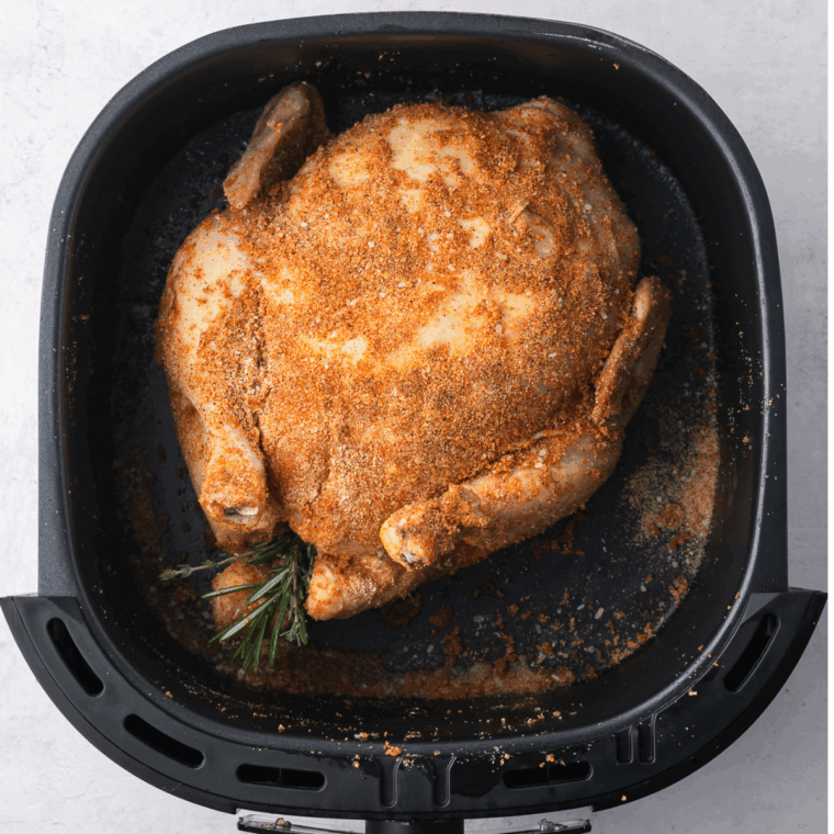Brushing whole chicken with olive oil and rubbing in a spice blend for even seasoning before air frying.