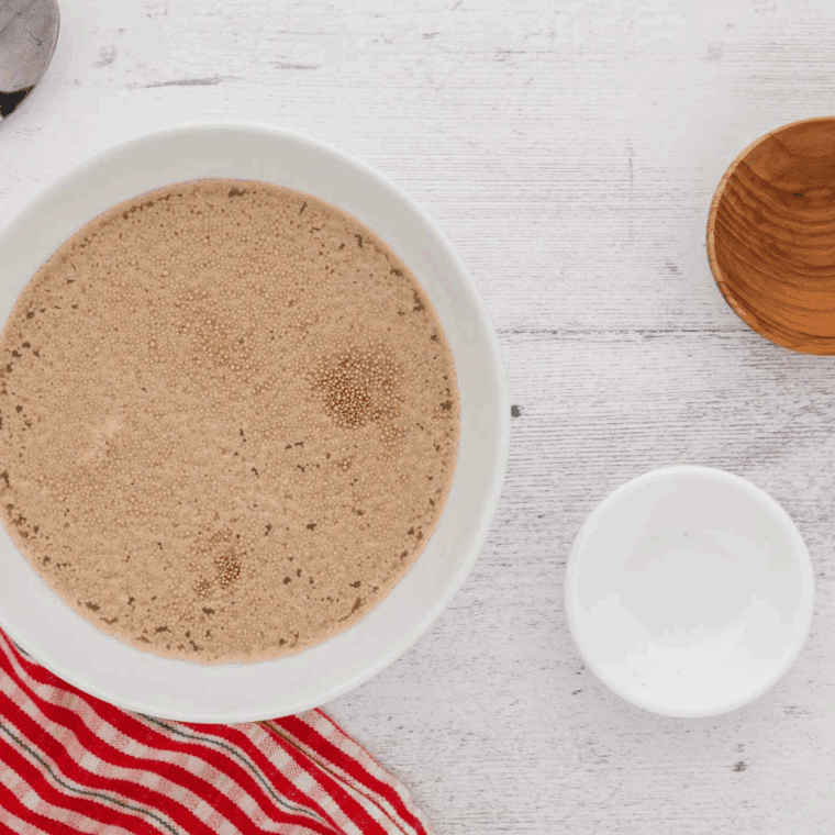 Combining warm water, active dry yeast, and sugar in a bowl until frothy for air fryer gluten-free bread.