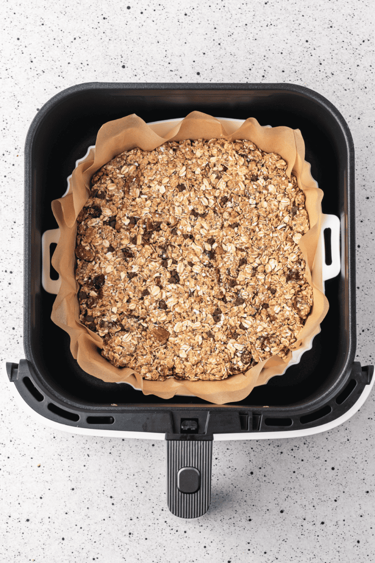 Placing the tray in the air fryer and cooking granola clusters until edges are golden and slightly crisp.