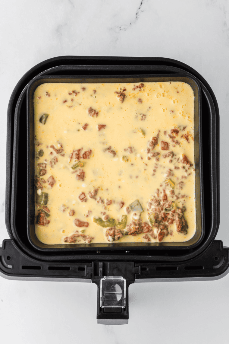 Pouring cooked beef mixture into a baking pan and adding egg mixture on top.