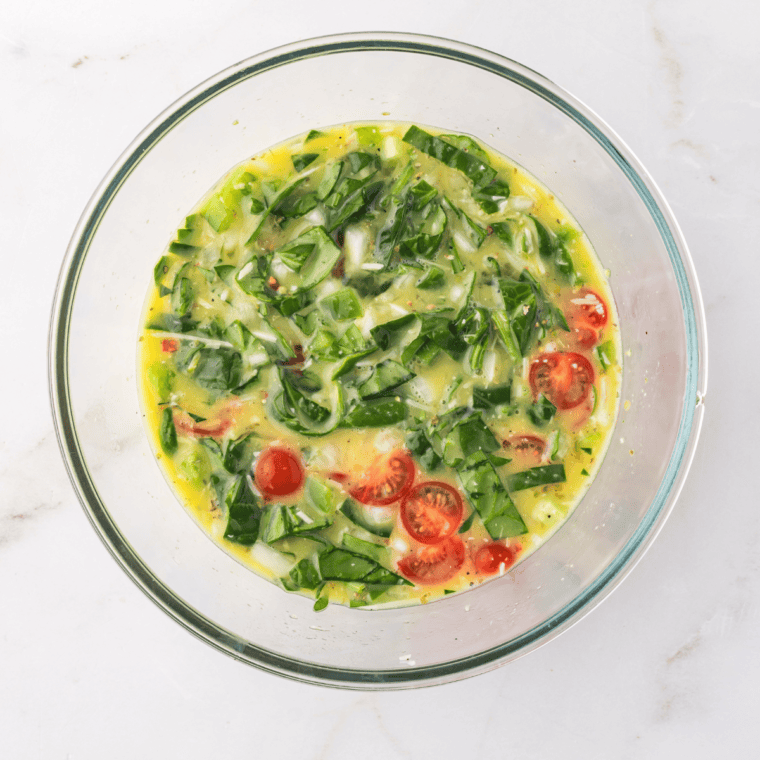 Whisking together eggs, milk, Parmesan cheese, garlic powder, oregano, salt, and pepper in a bowl until well combined.