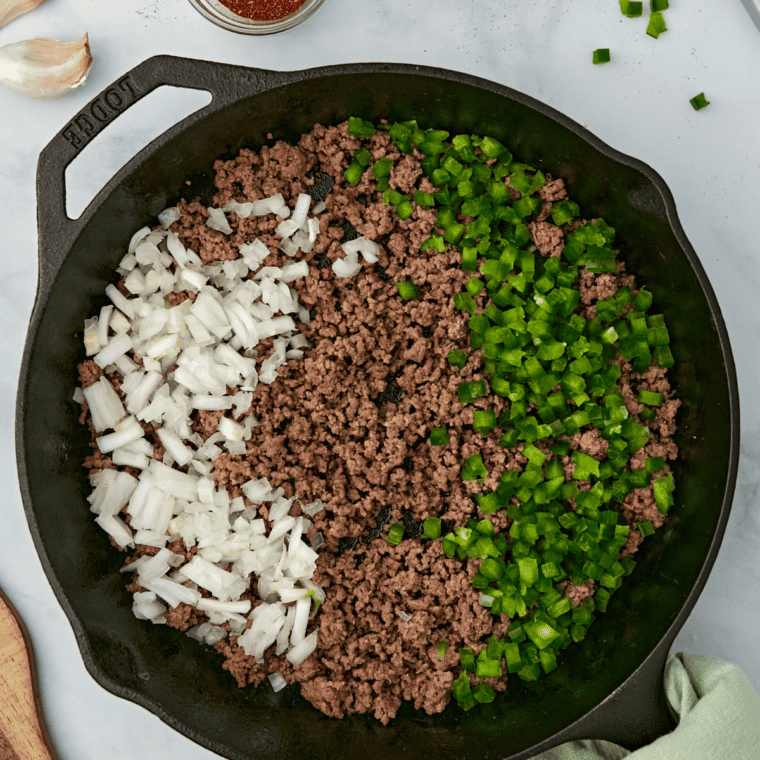 Cooking ground beef, bell pepper, and onion in a skillet, adding garlic and taco seasoning.