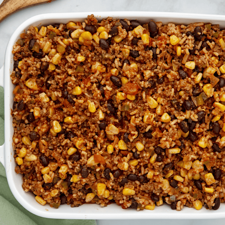 Spraying a casserole dish with cooking spray and adding the rice mixture.