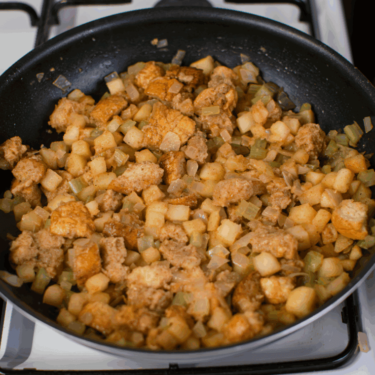 Sautéing diced apple, onion, and celery in melted butter, then adding cinnamon, nutmeg, salt, pepper, cubed bread, and chicken broth to make apple stuffing.