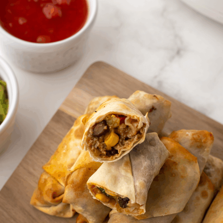 Air Fryer Taco Egg Rolls, crispy and golden on the outside, filled with seasoned beef, cheese, and taco toppings.