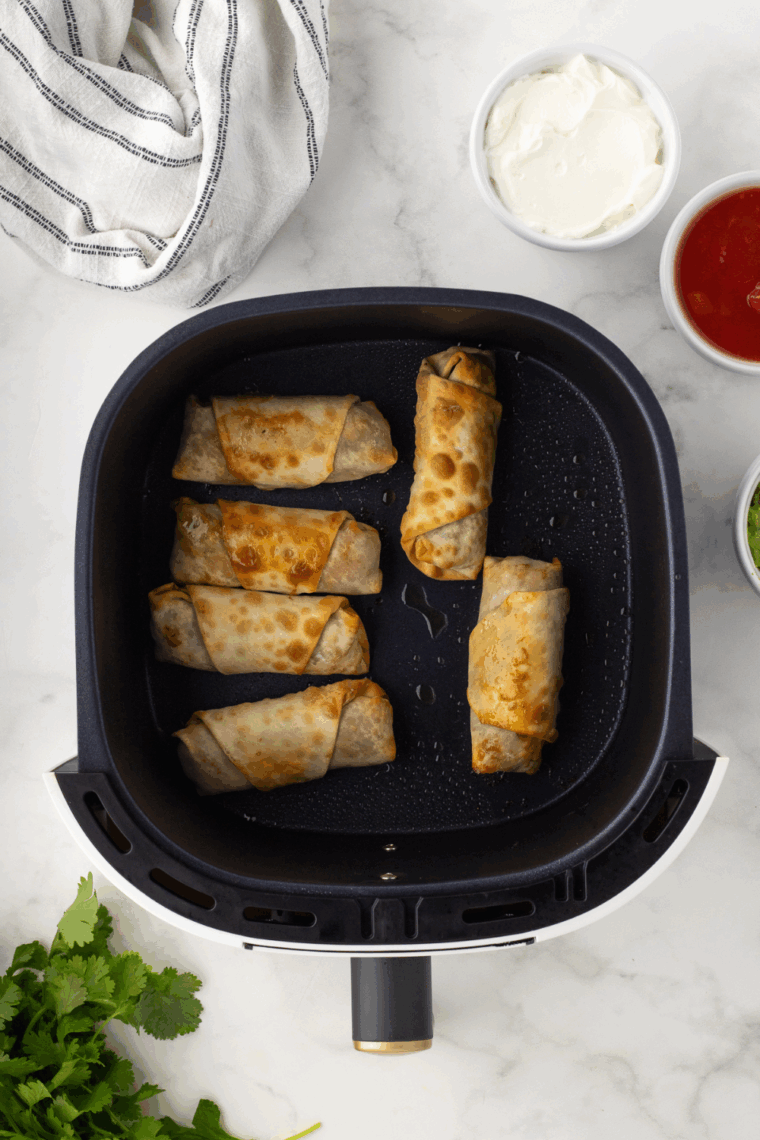 Allowing egg rolls to cool before serving with salsa, guacamole, and sour cream for dipping.