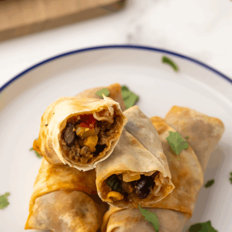 Air Fryer Taco Egg Rolls, golden and crispy, filled with seasoned beef, cheese, and taco toppings.