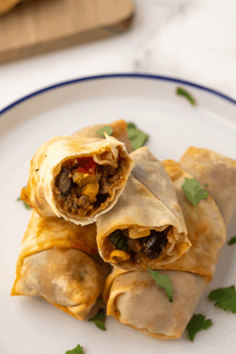 Air Fryer Taco Egg Rolls, golden and crispy with a savory filling of seasoned beef, cheese, and taco toppings.