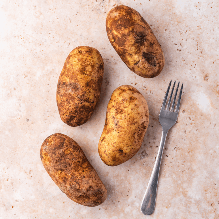 Scrubbing and pricking Russet potatoes with a fork before cooking.