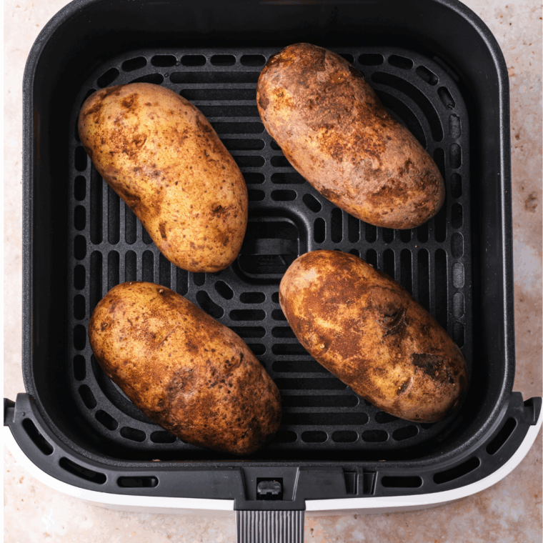 Placing potatoes in the air fryer basket and cooking at 400°F for 30-40 minutes until tender.