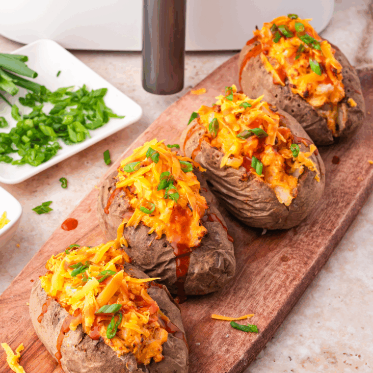 Air Fryer Twice Baked Buffalo Chicken Potatoes stuffed with buffalo chicken filling and topped with cheese.