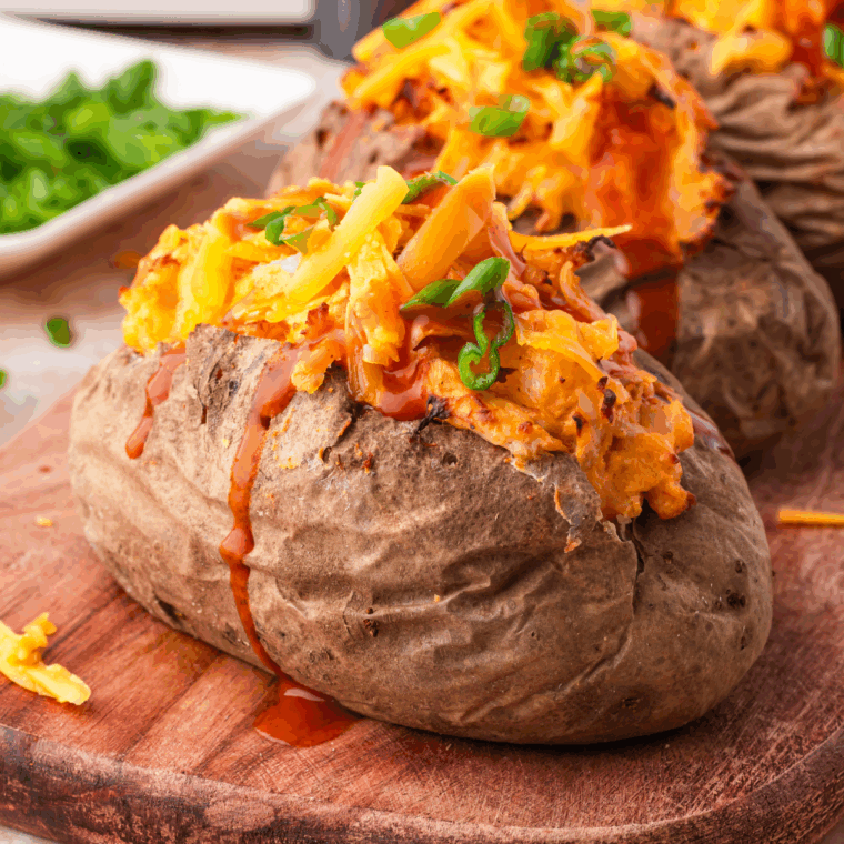 Air Fryer Twice Baked Buffalo Chicken Potatoes filled with buffalo chicken and topped with melted cheese.
