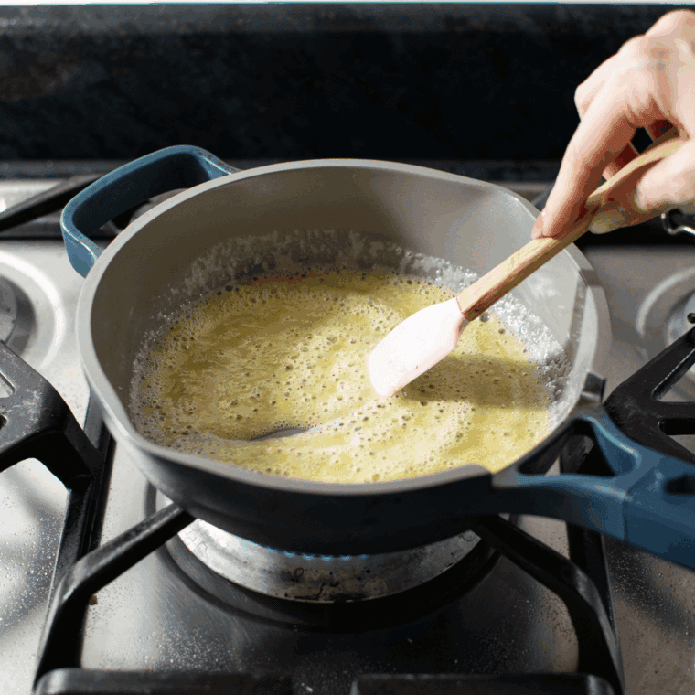 Melting butter in a saucepan, stirring in flour to form a roux, and gradually whisking in milk to thicken the mixture.