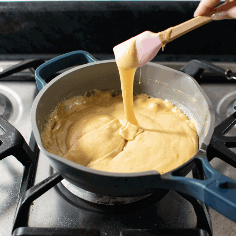 Stirring grated cheese, mustard, Worcestershire sauce, and optional beer into the sauce, then seasoning with salt, pepper, and paprika or cayenne.