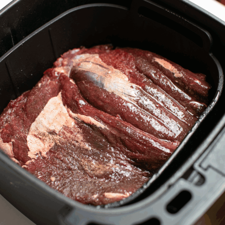 Rubbing chuck roast with olive oil, seasoning with salt and pepper, and searing in air fryer.