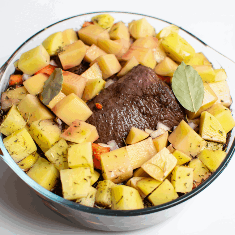 Peeling and cutting carrots and potatoes, dicing onion, mincing garlic, and arranging around roast.