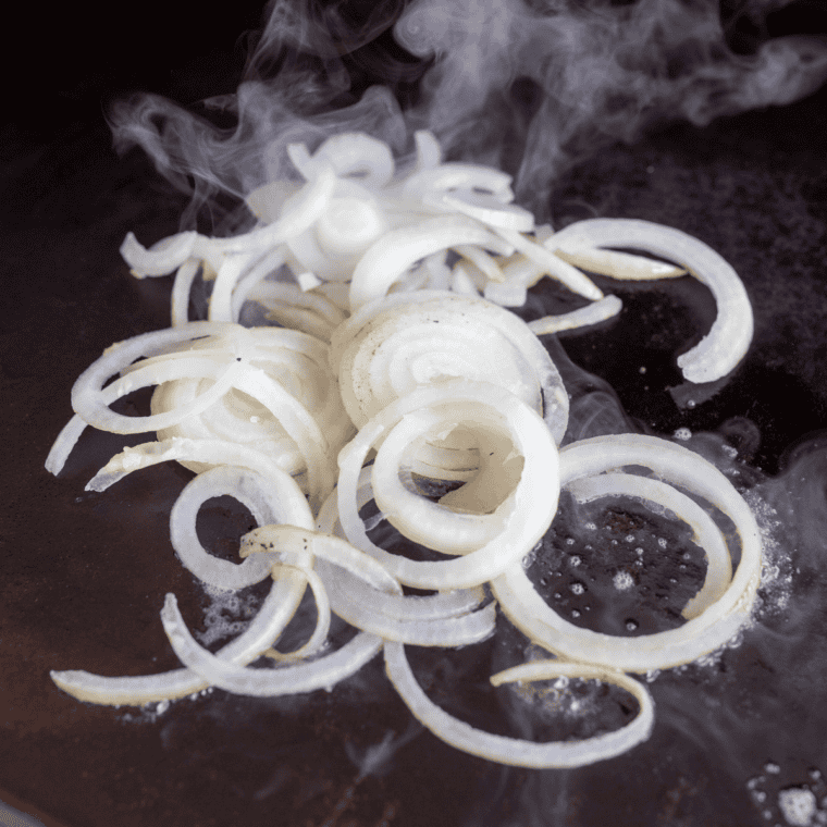 Melting butter and sautéing sliced onions until caramelized.