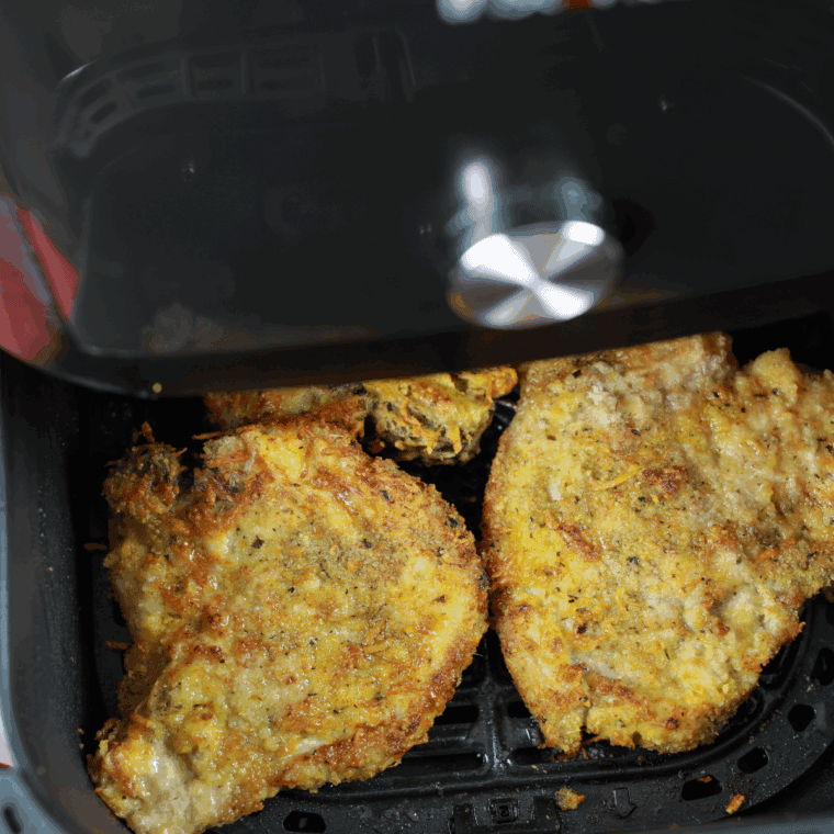 Cooked pork chops in the air fryer basket.