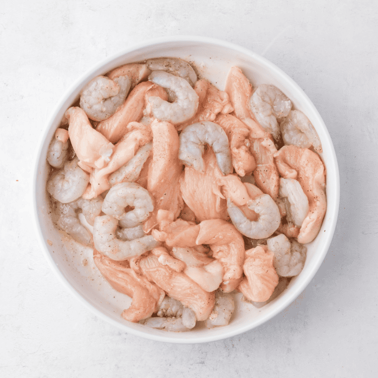 Toss chicken strips and shrimp with olive oil, garlic powder, salt, and pepper. Preheat air fryer to 375°F (190°C).