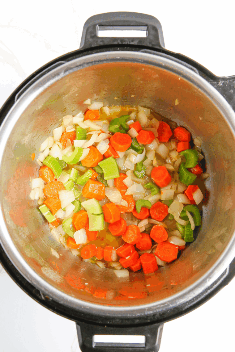 Sautéing onions, carrots, celery, and garlic in olive oil in Instant Pot.