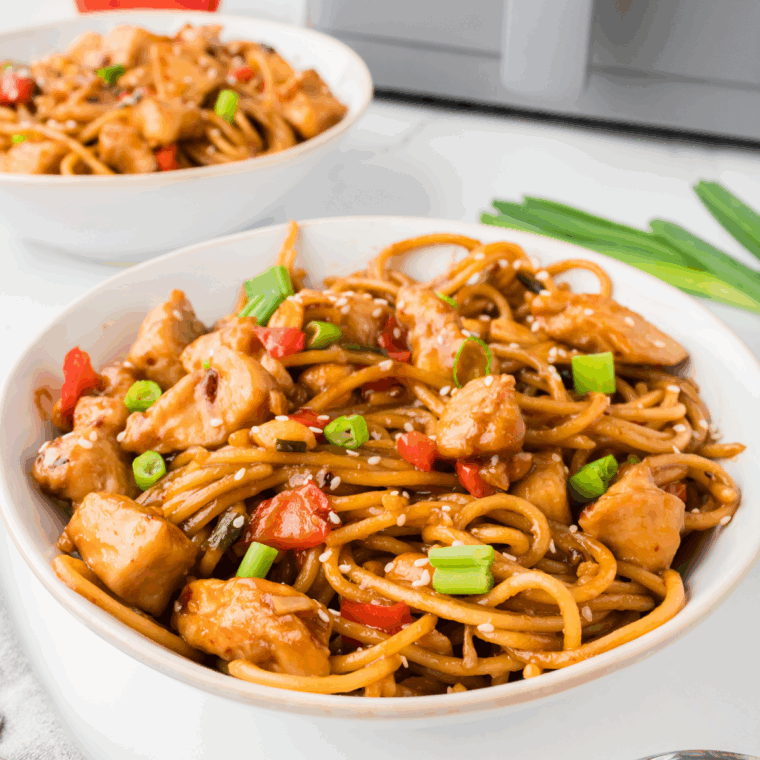 A plate of Kung Pao Chicken Spaghetti, featuring tender chicken, vegetables, and spaghetti in a savory, spicy sauce.