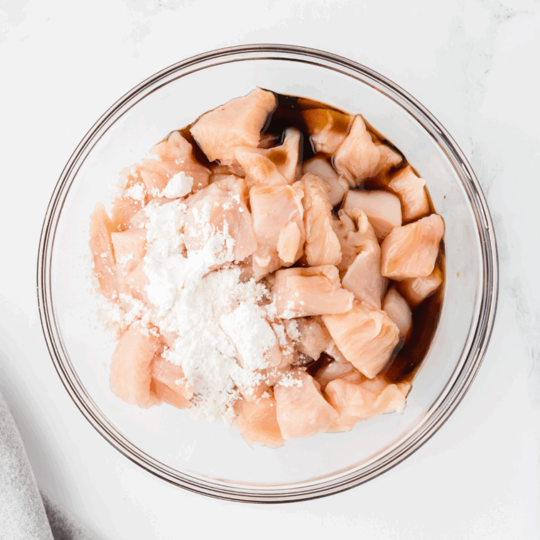 Marinating chicken with soy sauce and cornstarch, placing it in the air fryer basket, and cooking at 375°F.