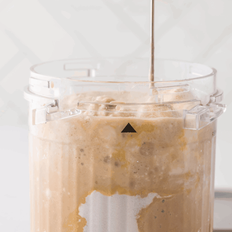 Using an immersion blender or whisk to combine almond milk and cold brew coffee until smooth and latte-like in color.