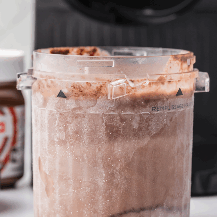 Pouring Nutella gelato mixture into a Ninja Creami pint container before freezing.