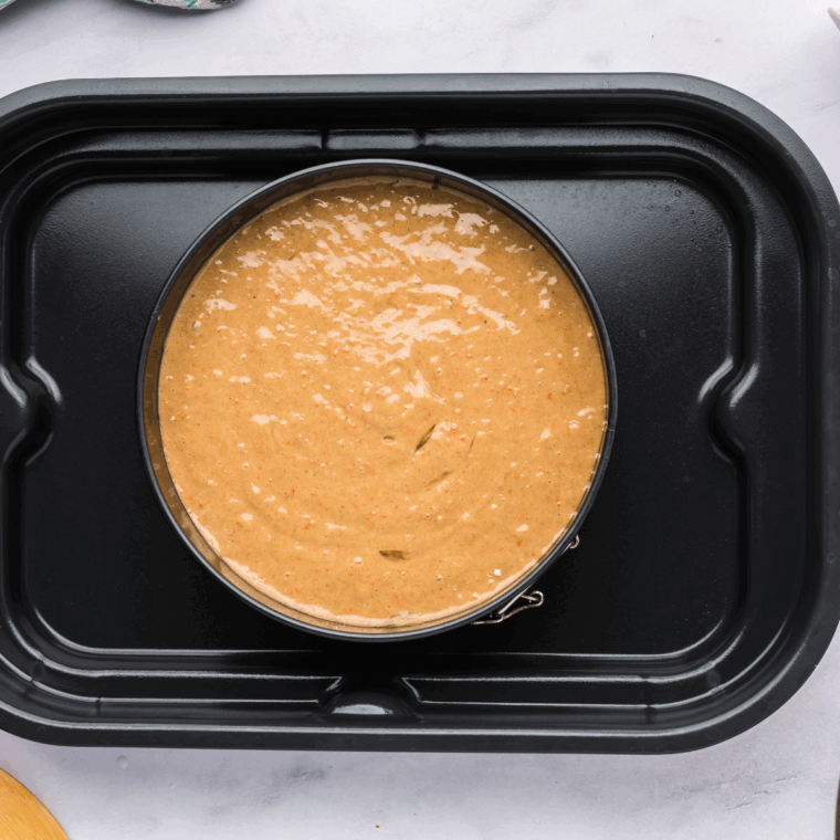 Placing the filled cake pan on the baking sheet.
