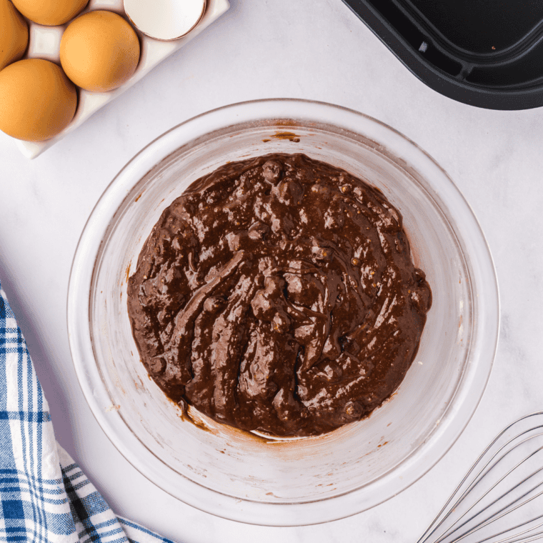Mixing brownie batter with eggs, water, oil, and optional chocolate chips or nuts.