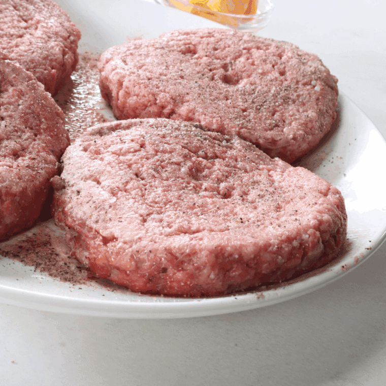 Seasoning ground beef with onion powder, garlic powder, salt, and pepper, and mixing well to evenly distribute the spices.