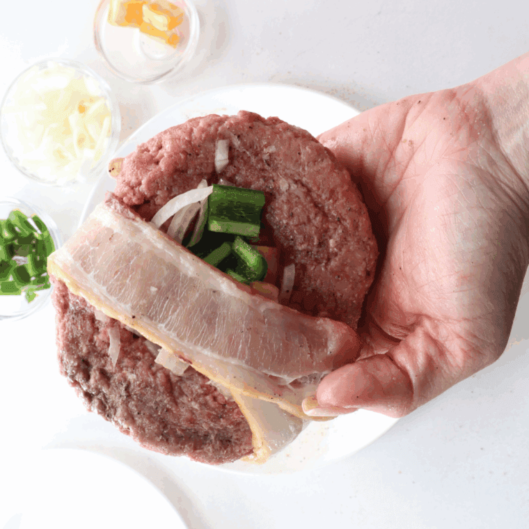 Wrapping partially cooked bacon strips around the edges of each burger patty and securing with toothpicks.