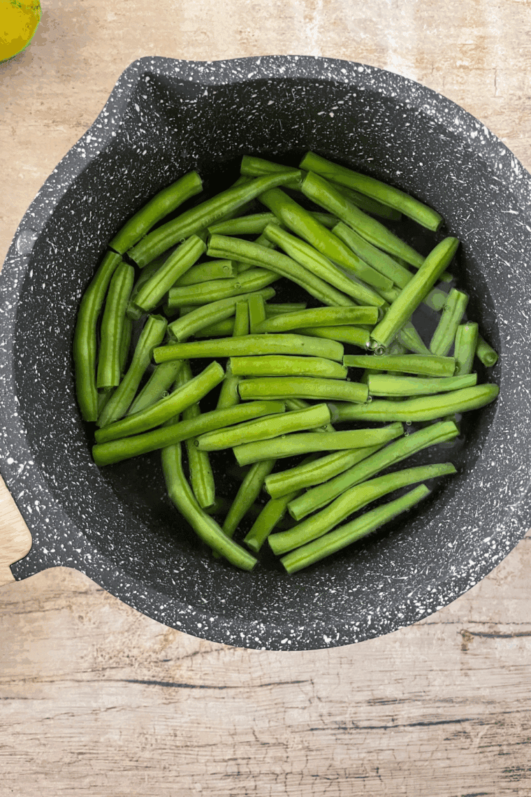 Fresh green beans being washed, trimmed, and patted dry before air frying.