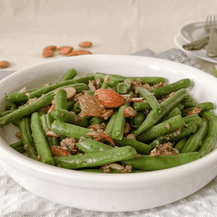 Air-fried green beans served in a dish, topped with toasted almonds and fresh lemon zest.