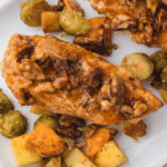 Golden air fryer chicken coated in crushed walnuts and drizzled with maple syrup, served on a white plate.