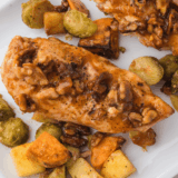 Golden air fryer chicken coated in crushed walnuts and drizzled with maple syrup, served on a white plate.