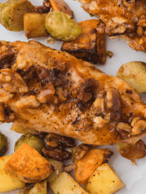 Golden air fryer chicken coated in crushed walnuts and drizzled with maple syrup, served on a white plate.