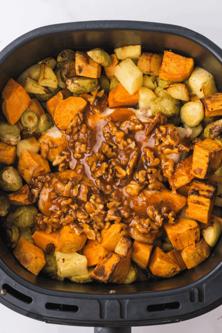 Fully cooked maple walnut chicken served with roasted vegetables and apples.