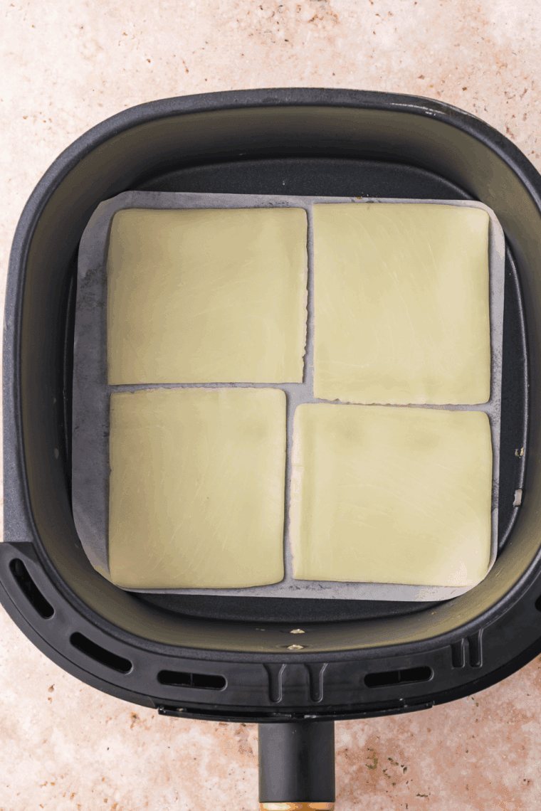 Place a slice of mozzarella cheese slice on the parchment paper.