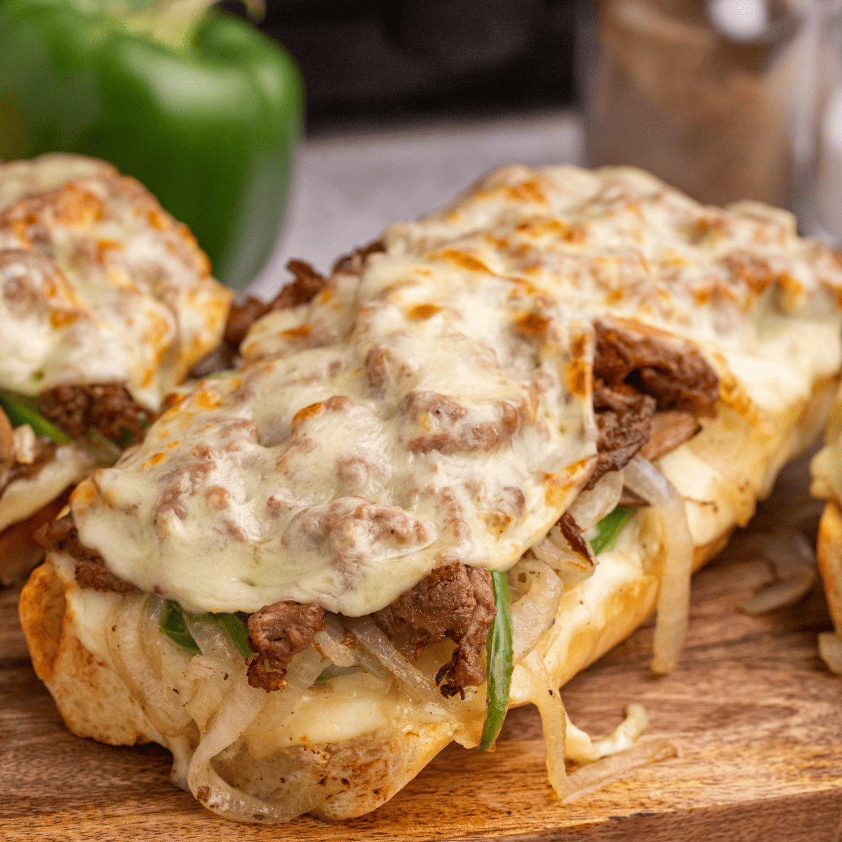 Air fryer Philly cheesesteak cheesy bread topped with sliced steak, melted cheese, peppers, and onions on a toasted baguette.