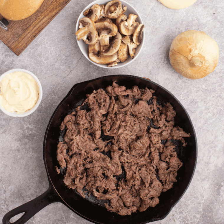 Cooking the shaved steak in the skillet.