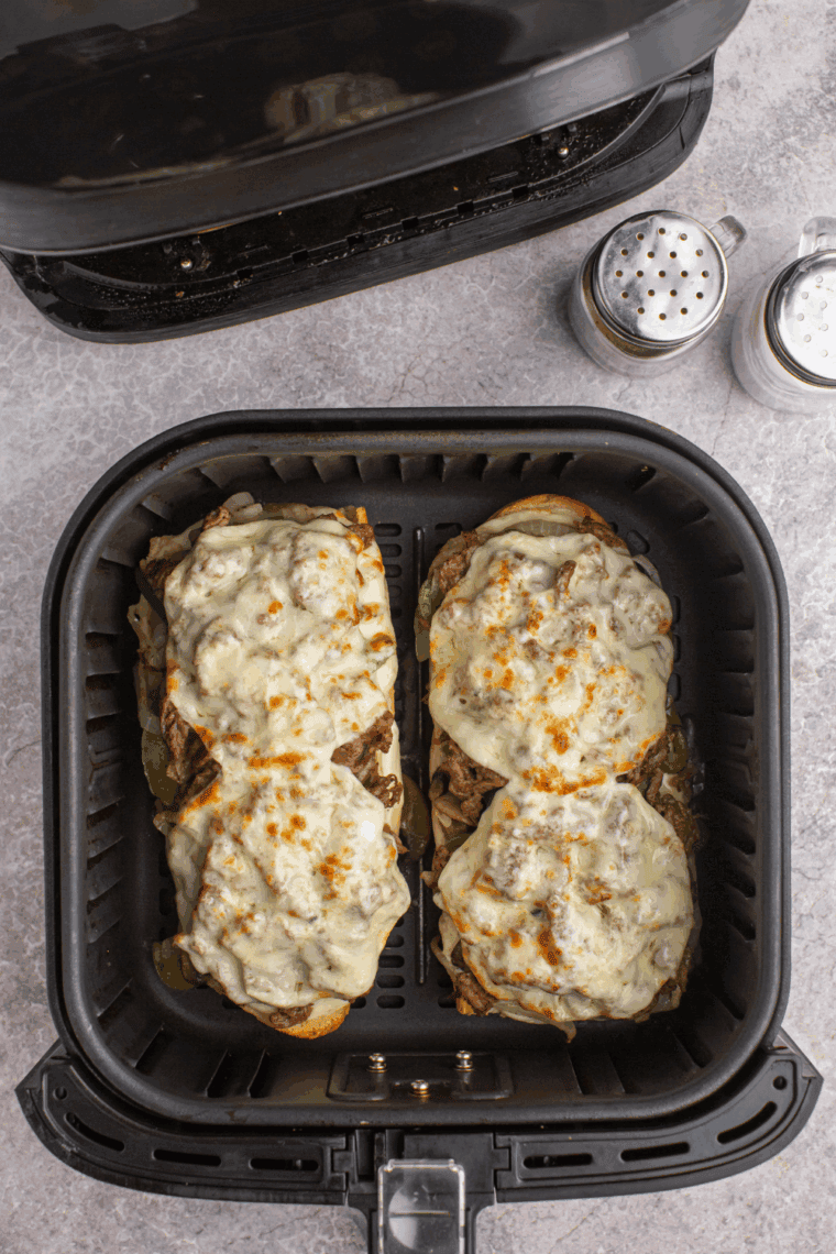 Air fryer Philly cheesesteak cheesy bread topped with melted provolone, steak, peppers, and onions on toasted bread.