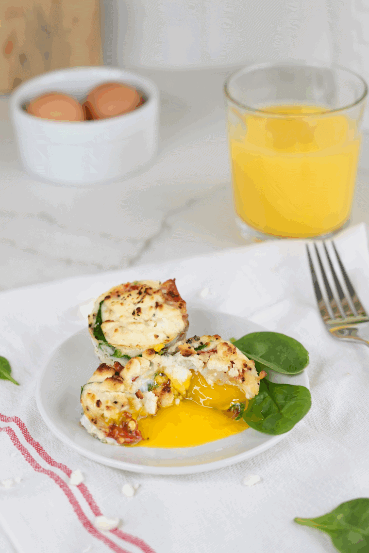 Golden frittata egg muffins filled with spinach, prosciutto, and goat cheese, served on a white plate.