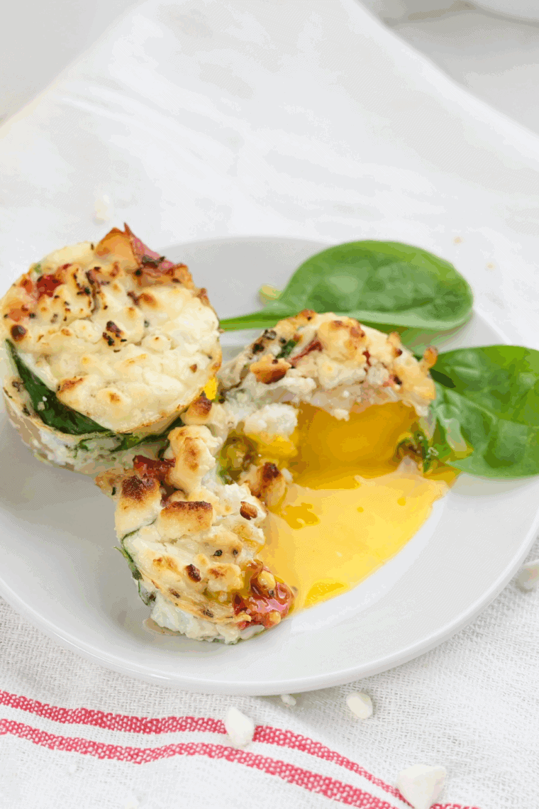 Freshly cooked frittata egg muffins filled with spinach, prosciutto, and goat cheese, arranged in an air fryer basket.