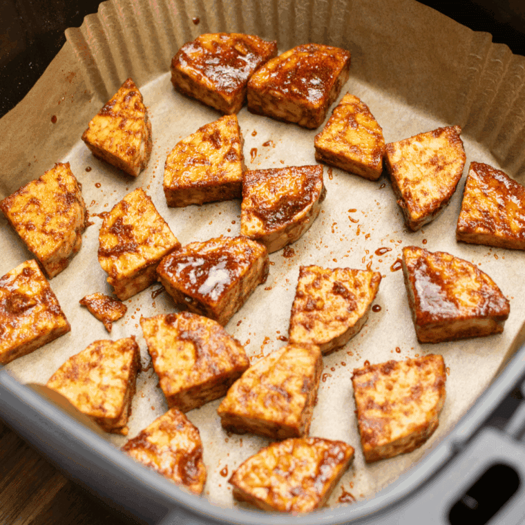 Arranging marinated tempeh in a single layer in the air fryer basket, cooking at 375°F for 10-12 minutes, shaking halfway through until golden and crispy.