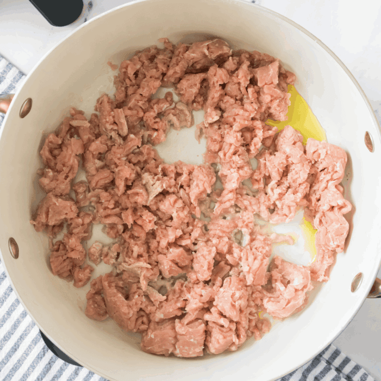 Sautéing turkey and olive oil in a large pot, adding diced onion and minced garlic, and cooking until vegetables are tender and translucent.