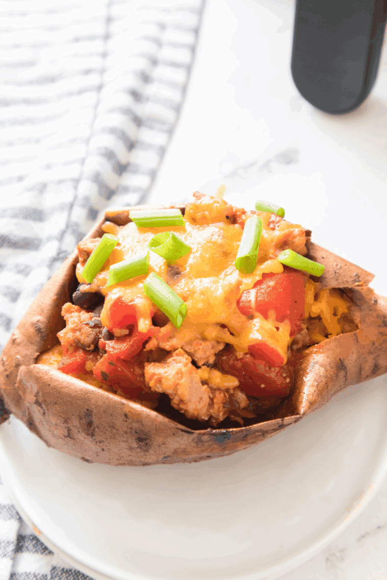 Air Fryer Turkey Chili Smothered Sweet Potatoes, topped with turkey chili, melted cheese, and garnished with cilantro and green onions, ready to serve for a delicious meal.