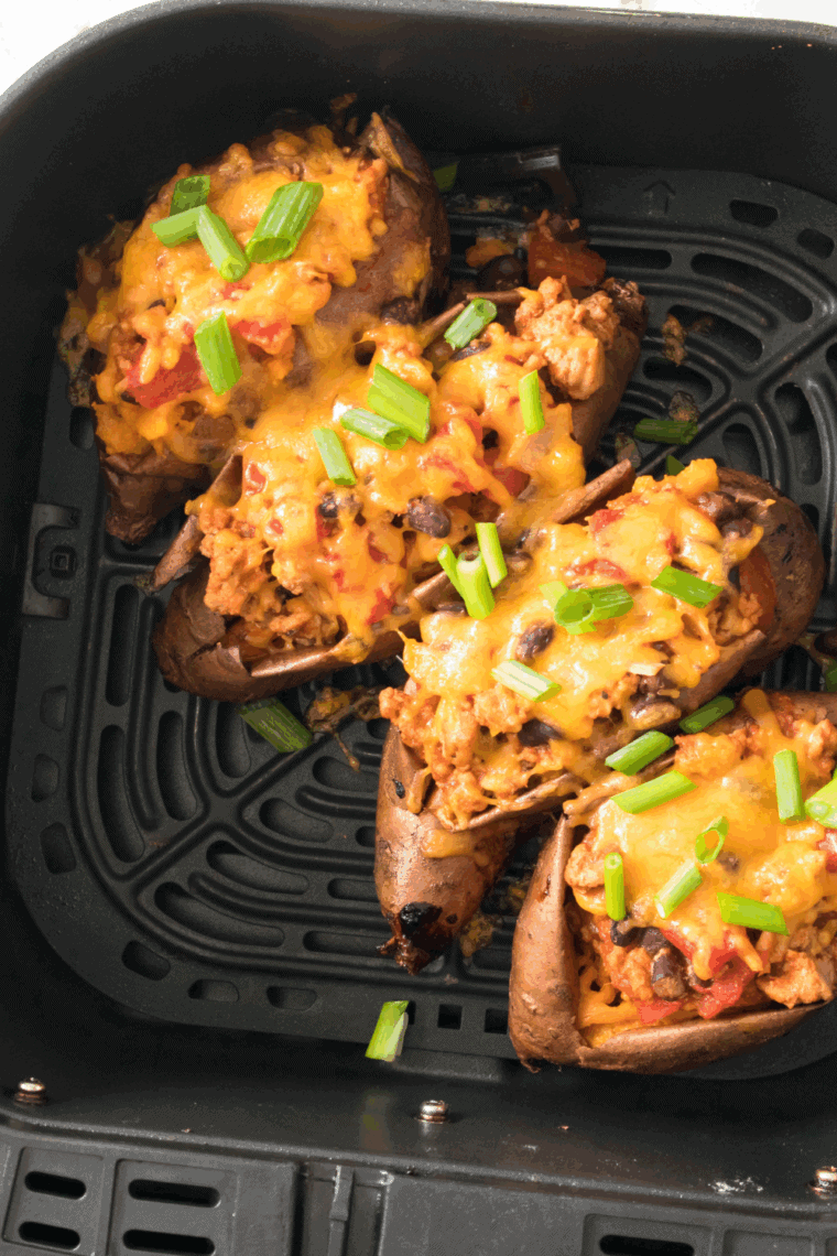 Air Fryer Turkey Chili Smothered Sweet Potatoes, topped with turkey chili and melted cheese, garnished with cilantro and green onions, perfect for a satisfying meal.