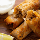 Golden, crispy homemade egg rolls filled with pork and vegetables, served with dipping sauce.